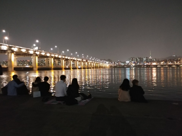 (사진=김나영 기자) 30일 서울 반포한강공원 둔치에서 시민들이 밤도깨비 야시장에서 구매한 음식을 먹고 있다.