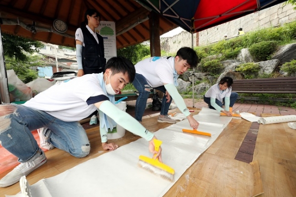 지난 13일 대우건설 대학생 홍보대사들이 서울시 성북구에 위치한 노후주택에 도배할 벽지에 풀을 바르고 있다. (사진=대우건설)