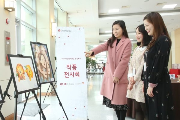 지난 15일 LG디스플레이 직원들이 희망날개클럽 후원 청소년들의 미술작품을 보고 있는 모습. (사진=LG디스플레이)