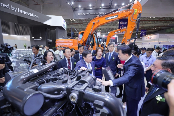 두산인프라코어 관계자가 응우옌 탄 퐁(Nguyen Thanh Phong) 호치민 인민위원회 위원장에게 GL11K 차량용 엔진 모델을 설명하고 있다. (사진=두산인프라코어 제공)