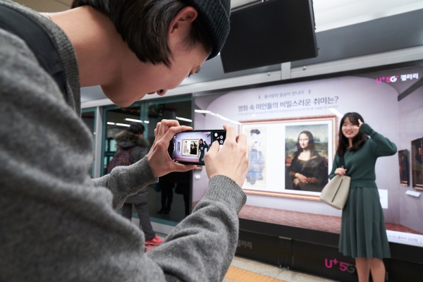 서울 지하철 6호선 공덕역에 마련된 세계 최초 5G기반 문화예술 공간 ’U+5G 갤러리’에 방문한 고객이 ‘U+AR’ 앱으로 작품을 체험하고 감상하는 모습. (사진=LG유플러스 제공)