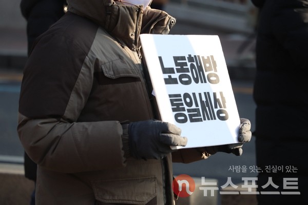 19일 이날 오전 서울 종로구 대학로에서 고(故) 백기완 통일문제연구소장의 운구행렬이 이어지는 가운데, 한 노동자가 ‘노동해방 통일세상’이라고 적힌 팻말을 들고 있다. (사진=뉴스포스트 이별님 기자)