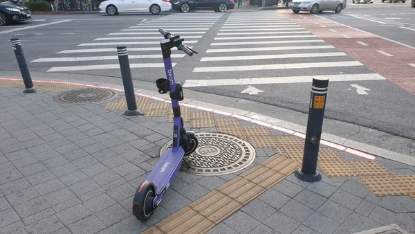 인도 곳곳 방치된 전동킥보드가 보행자들의 통행불편을 야기하고 있다. 횡단보도 집인부에 놓여있는 전동킥보드. (사진=뉴스포스트 홍여정 기자)