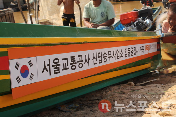 김동열 기관사 가족이 기부한 스크류 장착한 고깃배에 캄보디아 현지 가족이 앉아있다. (사진=밥퍼나눔운동본부 제공)