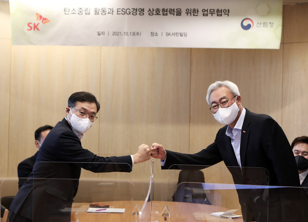 김준 SK수펙스추구협의회 환경사업위원회 위원장(오른쪽)과 최병암 산림청장이 13일 서울 종로구 서린동 SK빌딩에서 ‘탄소중립 활동과 ESG경영 상호협력을 위한 업무협약’을 체결한 뒤 주먹인사를 하고 있다. (사진=SK제공)