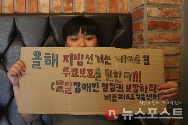 지난 24일 경기 과천의 한 카페에서 김기백 피플퍼스트성북센터 활동가가 발달장애인 참정권 보장을 촉구하며 피켓을 들고 있다. (사진=뉴스포스트 이별님 기자)