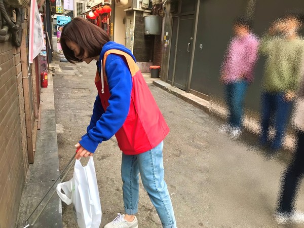 오진화 PM이 흡연가들 사이로 들어가 담배꽁초를 줍고 있다. (사진=뉴스포스트 이상진 기자)