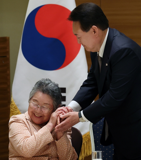 19일 윤석열 대통령이 히로시마 한 호텔에서 열린 히로시마 동포 원폭 피해자와의 간담회에서 박남주 한국원폭피해대책특별위 전 위원장의 손을 잡고 있다. (사진=뉴시스)