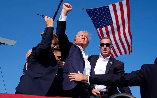 도널드 트럼프 전 미 대통령이 13일(현지시각) 펜실베이니아주 버틀러에서 집회 도중 암살 시도가 분명한 총격으로 오른쪽 귀에서 피를 흘리면서도 불끈 쥔 주먹을 흔들며 "싸우자"고 외치고 있다. 그는 곧바로 경호요원들에 이끌려 대피했다. (사진=뉴시스/AP)